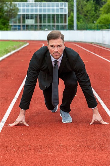 Man in a suit on a running track in starting position