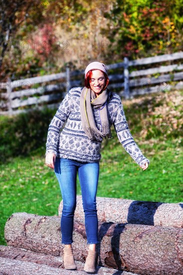 Portrait of a woman balancing on tree trunks outside