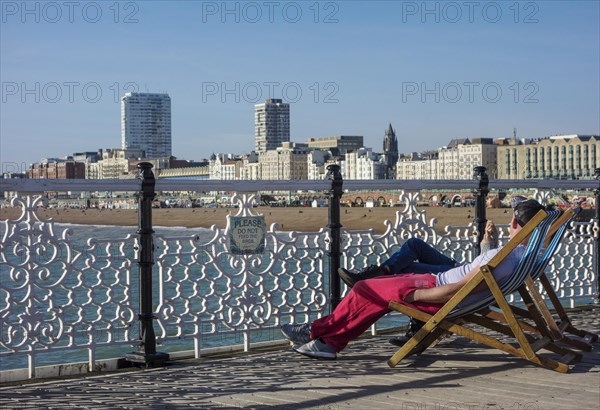 Tourists sitting on deckchairs on Brighton pier