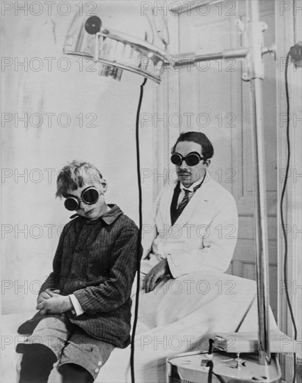 1930 photograph showing doctor and child patient with goggles during light therapy