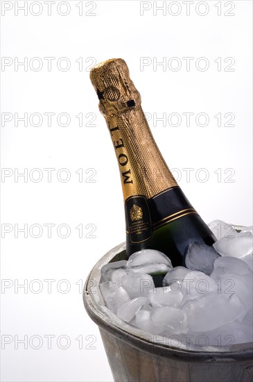 Bottle of champagne in ice bucket full of ice and two empty champagne flutes