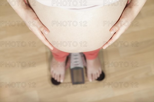 Pregnant woman standing on a bathroom scale