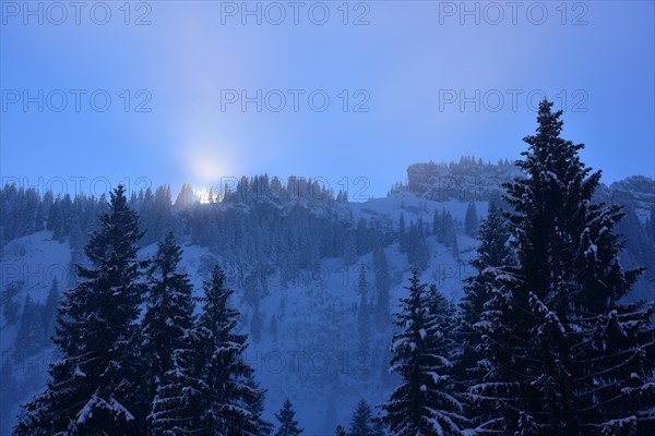 The sun breaks through the high fog at the Riedberg Pass near Obermaiselstein in Allgaeu