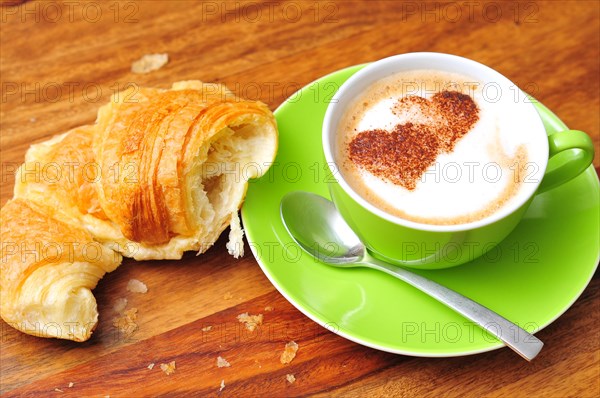 Cup of capuccino dusted with cocoa powder in the shape of a heart