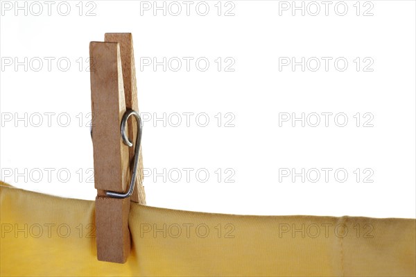 Wooden clothes peg or pin securing a yellow t-shirt on clothes line