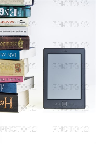 Kindle e reader with a large pile of books