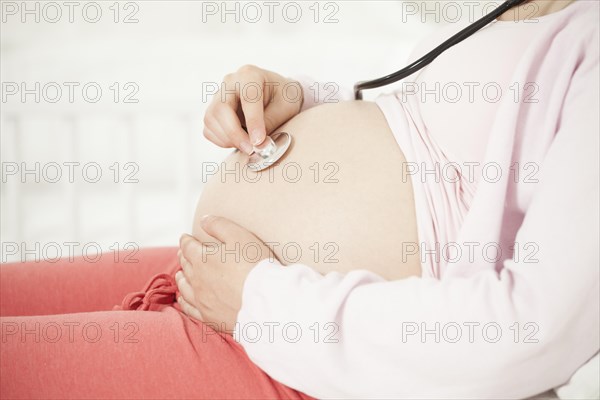 Pregnant woman with stethoscope on baby belly | MR:yes NH_pregnant_belly_mr