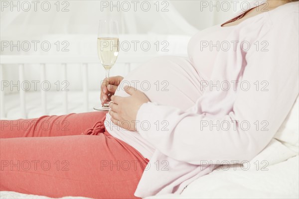 Pregnant woman with a champagne glass on her baby bump