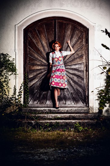 Portrait of a woman in dirndl in front of a wooden wall