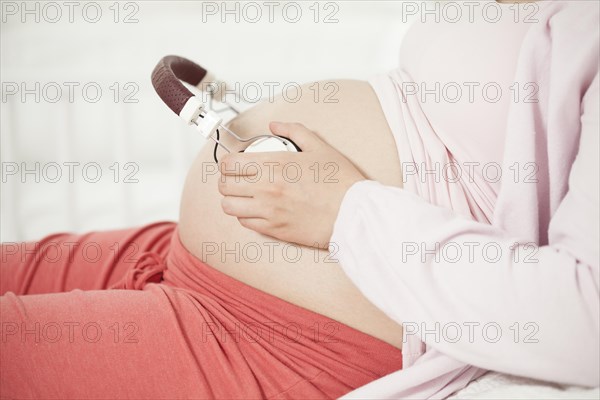 Pregnant woman with headphones on baby belly | MR:yes NH_pregnant_belly_mr