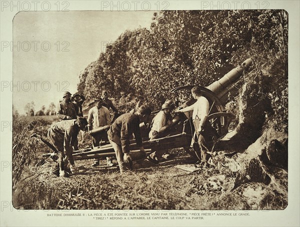 Artillery soldiers firing battery cannon from behind camouflage screen towards battlefield in Flanders during the WWI