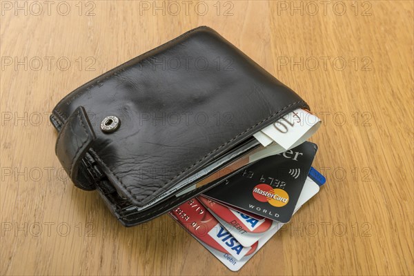 Mans old leather wallet with credit cards and pound sterling banknotes