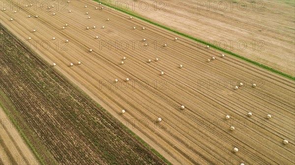 Aerial view of a harvested grain field with straw bales near Augsburg in Swabia