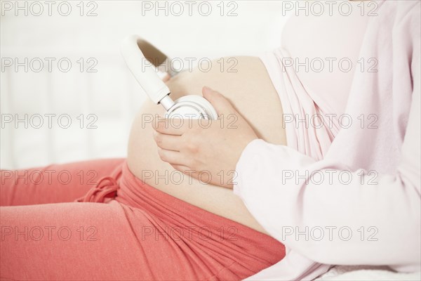 Pregnant woman with headphones on baby belly | MR:yes NH_pregnant_belly_mr