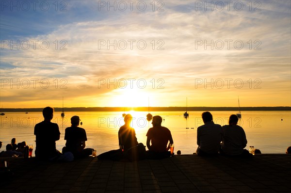 Silhouettes of people at sunset on the shore of the Lake Ammer