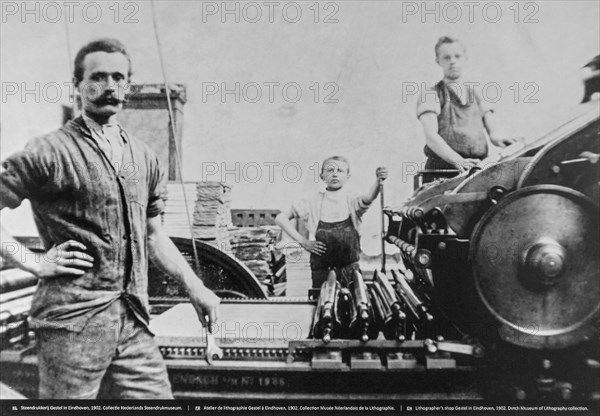 1902 black and white archival photo showing pressman and children working on lithographic printing press in pressroom