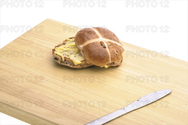 Hot cross bun with knife on a wooden board