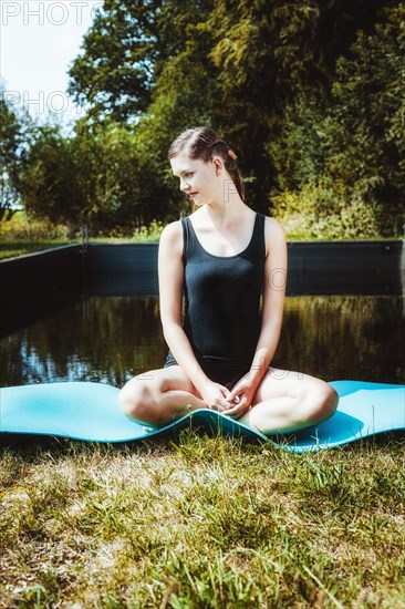 Woman sitting cross-legged in front of a swimming pool | MR:yes 280818NicoleSDEU