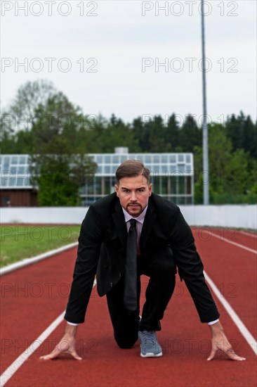 Man in a suit on a running track in starting position