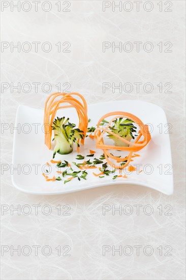 White plate decorated with carving of yellow beetroot and courgette