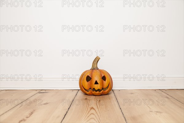 Grinning Clay Pumpkin on Wooden Floor