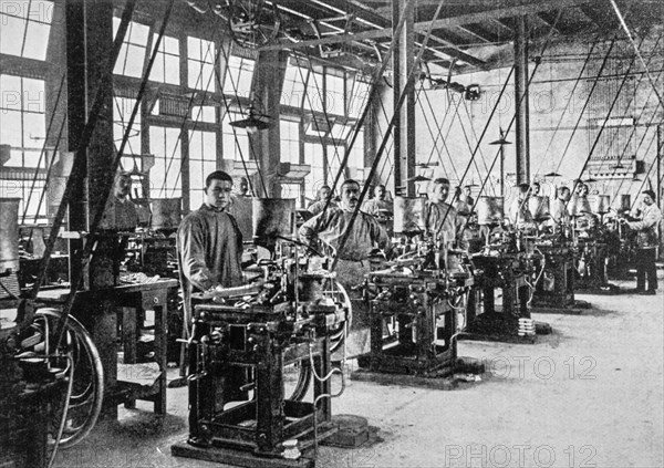 Early 20th century black and white archival photo showing workers and machines for casting types for typesetters at foundry floor of type foundry