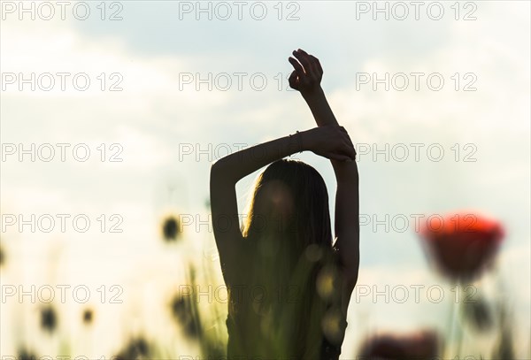 Silhouette of Girl rising hands against sun