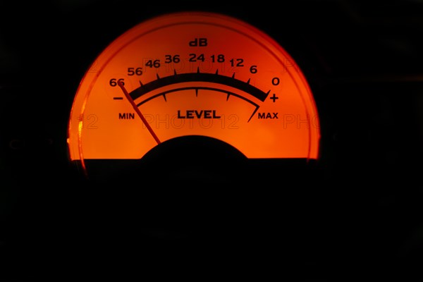 Decibel meter of a sound amplifier illuminated orange on black background