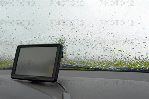 Inside of a car with rain on windshield window and GPS navigation system in bad weather