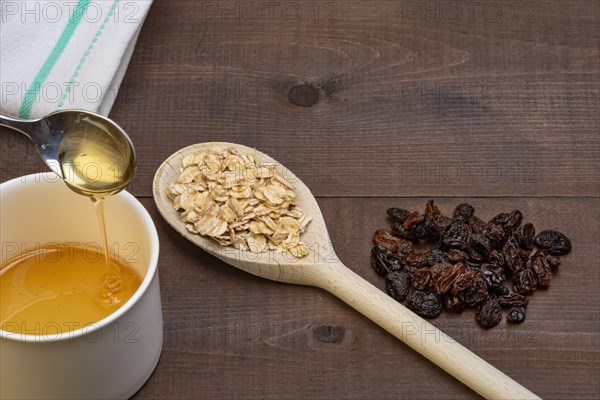 Wooden spoon with rolled porridge oats on a wooden background