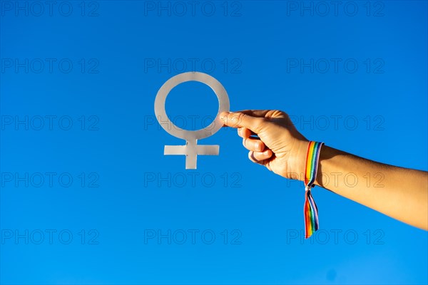 Blue sky background with a hand of a woman with female symbol in favor of feminism