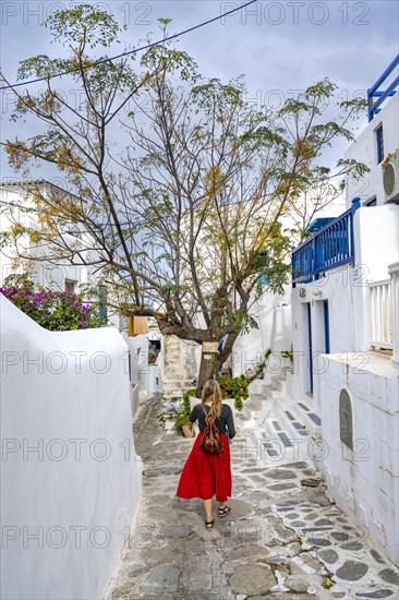 Young woman with red skirt in the alleys of the old town Chora