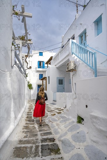 Young woman with red skirt in the alleys of the old town Chora