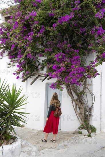 Young woman with red skirt in the alleys of the old town Chora