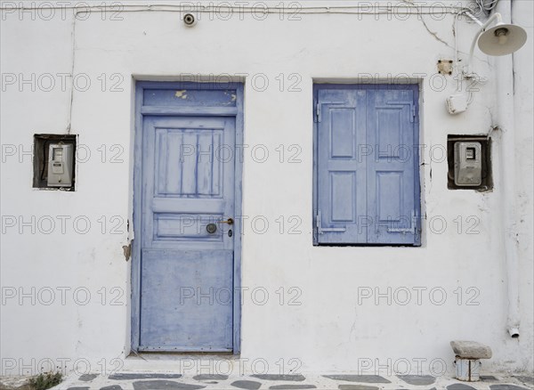 House facade with blue entrance door and shutters