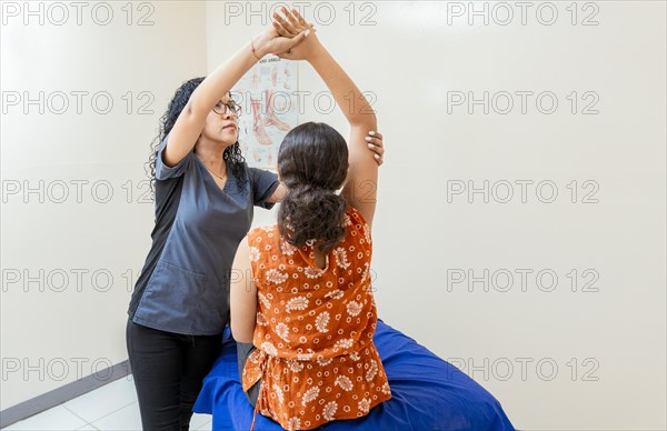 Young physiotherapist rehabilitating patient elbow in assisted living center