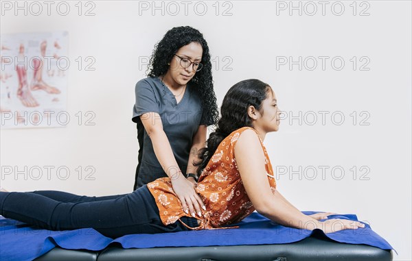 Young physiotherapist assisting female patient with lower back pain