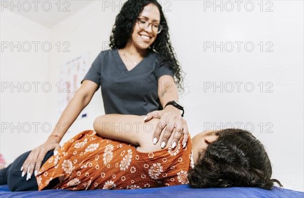 Physiotherapist rehabilitating shoulder to patient lying on her side