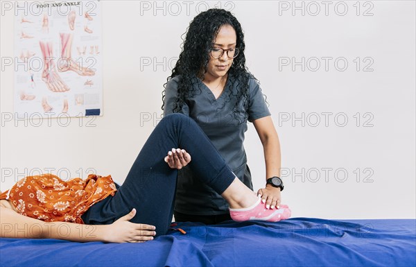 Worker in modern physiotherapy assisting female patient