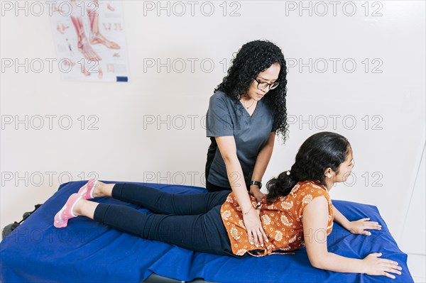 Woman performing lumbar physiotherapy to patient