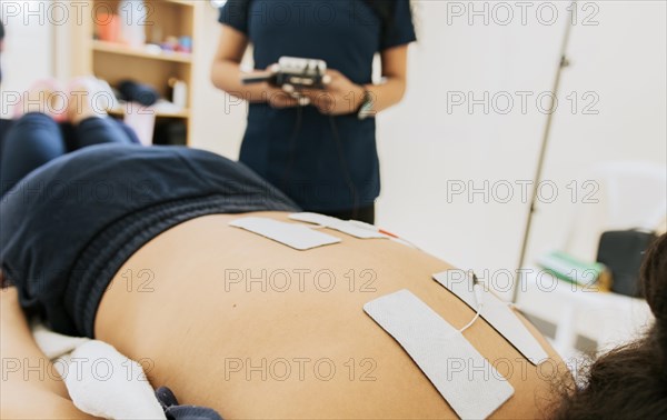 Physiotherapist electrostimulating a patient