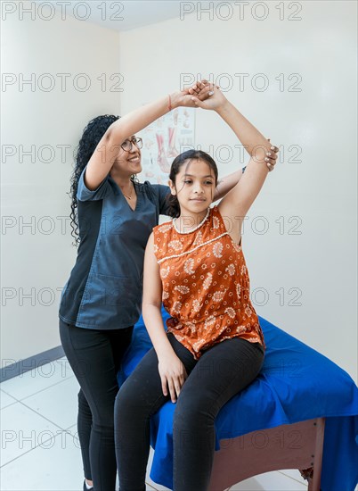 Physiotherapist with female patient rehabilitating elbow