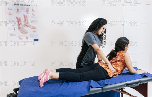 Physiotherapist assisting lumbar treatment to lying patient