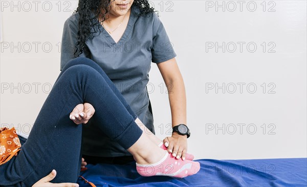 Professional physiotherapist assisting patient in leg rehabilitation