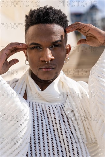 A young man of African ethnicity in a white contemporary suit and black leather boots