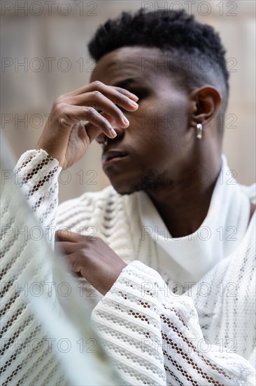 A young man of African ethnicity in a white contemporary suit and black leather boots