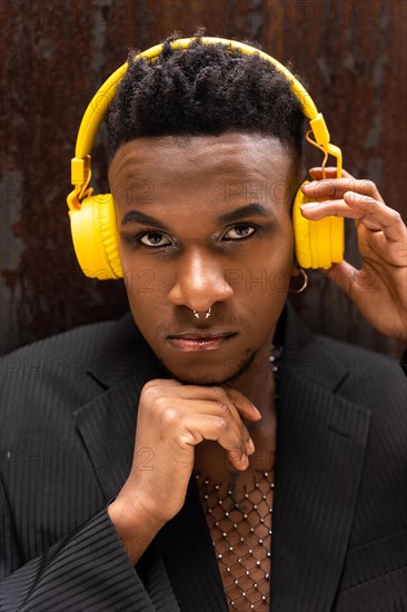 Portrait of a black ethnic man listening to music in wireless yellow headphones