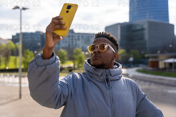 A black ethnic man with a phone and a blue jacket in the city
