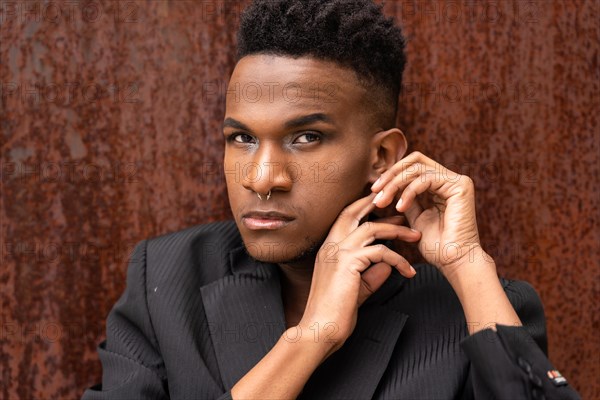 Portrait of a model man of black ethnicity in a fashion pose on a brown metallic background