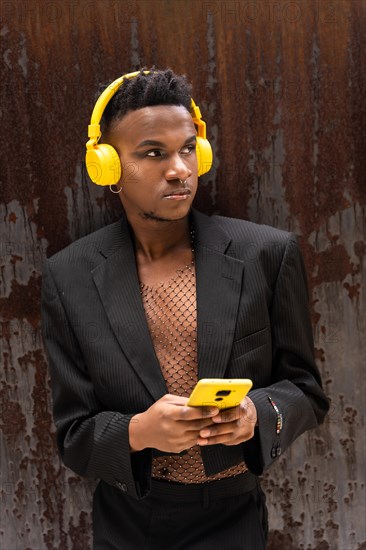 A man of black ethnicity listening to music wireless yellow headphones